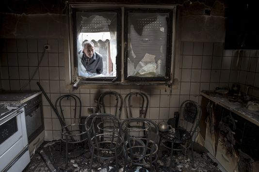 Un homme regarde à travers la fenêtre d'une maison détruite à Kumanovo en Macédoine.